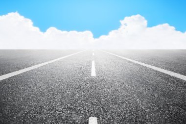 Asfaltlı karayolu üzerinde beyaz bulutlar arka plan mavi gökyüzü