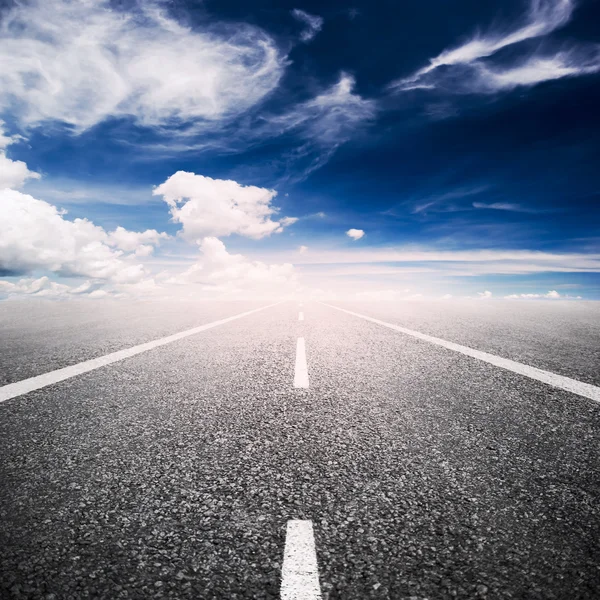 Ασφαλτοστρωμένος αυτοκινητόδρομος πάνω από το γαλάζιο του ουρανού με φόντο άσπρα σύννεφα — Φωτογραφία Αρχείου