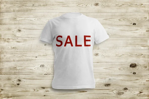 White shirt with inscription SALE over wood background — Stock Photo, Image