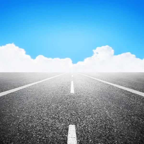 Strada asfaltata sopra cielo blu con sfondo nuvole bianche — Foto Stock