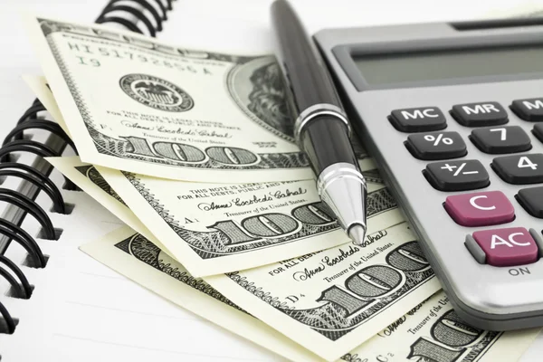 Pen, calculator and dollars on notebook — Stock Photo, Image