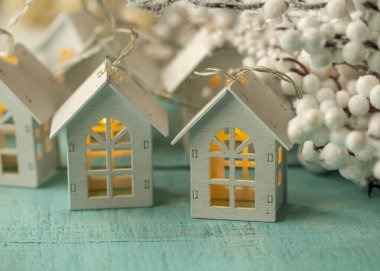 Turkuaz ahşap bir yüzeyde parlak bir çelenk ahşap ev.