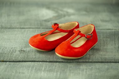 Koyu ahşap yüzeyde dekor ve arka plan olarak kırmızı bebek ayakkabıları, yeni doğanlar için Noel süslemeleri.