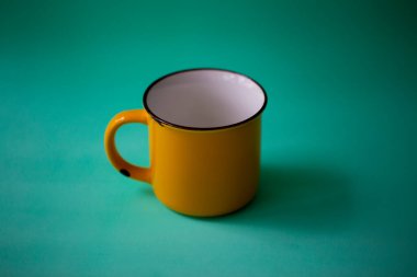 Naneli turkuaz arka planda çay ya da kahve için sarı demir bardak.