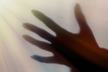 Boyalı bir duvarda bulanık bir el gölgesi, bir kadının elinin gölgesi.