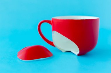 Kırık kırmızı bardak mavi arka planda, boşanma sembolü, kayıp, yakın plan