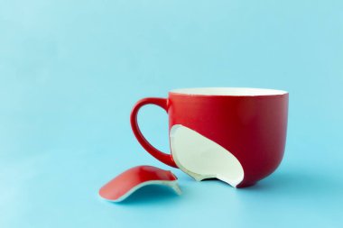 Kırık kırmızı bardak mavi arka planda, boşanma sembolü, kayıp, yakın plan