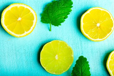 Masanın turkuaz yüzeyinde naneli ve buzlu dilimlenmiş limon, yakın plan.