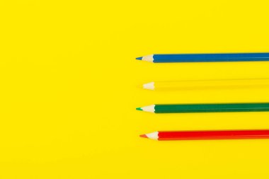 Sarı arkaplanda renkli kalemler, yakın plan.