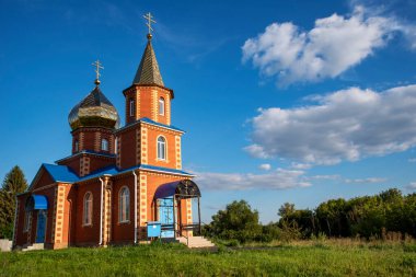 Kırmızı tuğlalardan yapılmış ortodoks kilisesi mavi gökyüzünün arka planında bulutlu