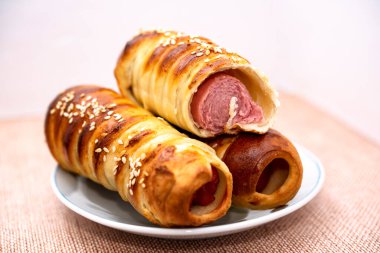 Bir tabakta hamur içinde ısırılmış sosis, yakın plan, yatay.