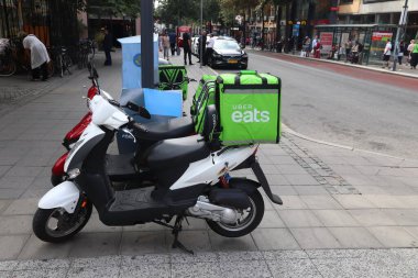 STOCKHOLM, SWEDEN - 23 Ağustos 2018: Stockholm, İsveç 'te Uber yemek dağıtım motosikleti yiyor. Bu yemek servisi Uber sürüş paylaşım şirketinin bir parçasıdır..