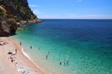 KONAVLE, CROATIA - 28 Haziran 2019: İnsanlar Hırvatistan 'ın Dalmaçya bölgesindeki Konavle bölgesindeki kayalıkların altındaki Pasjaca plajında tatil yapıyorlar.