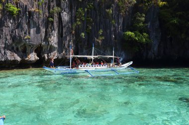 PALAWAN, PHIPPINES - 1 Aralık 2017: Turistler Filipinler, Palawan 'daki ada gezisinde bangka teknesine binerler. 2016 yılında Filipinleri 6 milyon yabancı turist ziyaret etti.