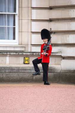 LONDON, İngiltere - 23 Nisan 2016: Kraliçe 'nin Muhafızları Londra, İngiltere' deki Buckingham Sarayı önünde devriye geziyor. Geleneksel üniformalı muhafızlar İngiltere 'nin önemli bir sembolüdür..