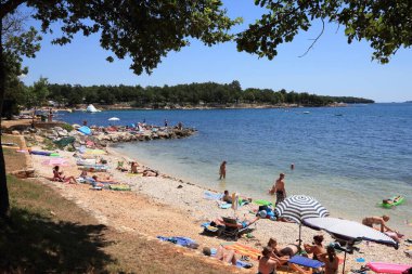 POREC, CROATIA - 20 Haziran 2011: İnsanlar Hırvatistan 'ın Porec kentindeki plajın tadını çıkarıyor. 2011 yılında çoğu yaz olmak üzere 11 milyon turist Hırvatistan 'ı ziyaret etti..