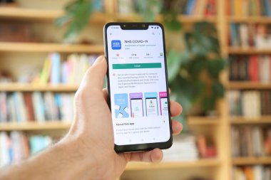 WARsaw, POLAND - 29 Ocak 2021: Android OS, Xiaomi markalı akıllı telefona NHS Covid-19 uygulaması yükleyen kullanıcı. Birleşik Krallık 'taki resmi hükümet koronavirüs pandemik yönetim uygulaması..