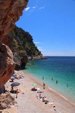 KONAVLE, CROATIA - 28 Haziran 2019: İnsanlar Hırvatistan 'ın Dalmaçya bölgesindeki Konavle bölgesindeki kayalıkların altındaki Pasjaca plajında tatil yapıyorlar.