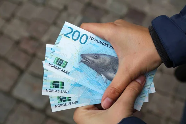 Norwegian krone banknotes. Hands holding 200 kroner paper money in Norway.