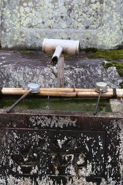 Japan culture - purification water fountain with metal ladles at a Buddhist temple in Arashiyama, Kyoto.