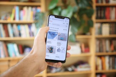 WARA, POLAND - 29 HAZİRAN 2021: Android işletim sisteminde, Xiaomi akıllı telefonunda kullanıcı tarayan el yapımı küpe Etsy pazar yeri. Etsy, el işi ürünleri üzerine uzmanlaşmış bir online pazar yeri..