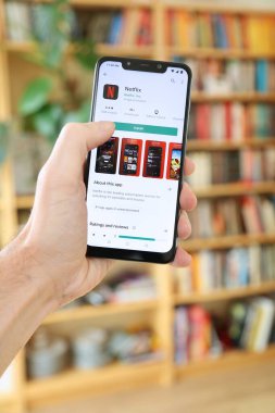 WARsaw, POLAND - 29 Ocak 2021: Android OS, Xiaomi akıllı telefon üzerinde Netflix film ve TV akış mobil uygulaması yükleyen kullanıcı.