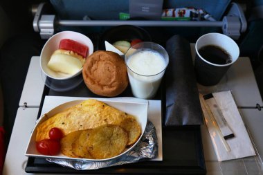 Türkiye 'de havayolu kahvaltısı. Ekmek rulosu, patates ve domatesli omlet, meyve kutusu, ayran içeceği ve bir fincan kahve..