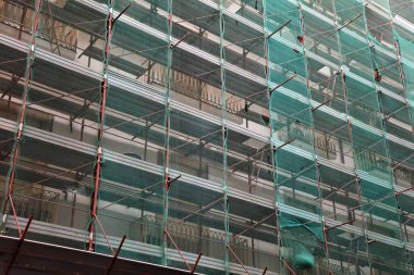 Catania, İtalya 'da inşaat alanında koruyucu plastik ağ ile kaplı bir yapı iskelesi var. Bina yenileme çalışmaları.