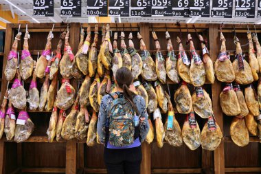 MADRID, SPAIN - 13 Nisan 2025: Müşteriler Madrid, İspanya 'da bir markette kurutulmuş domuz budu türündeki jambonlara bakıyorlar.