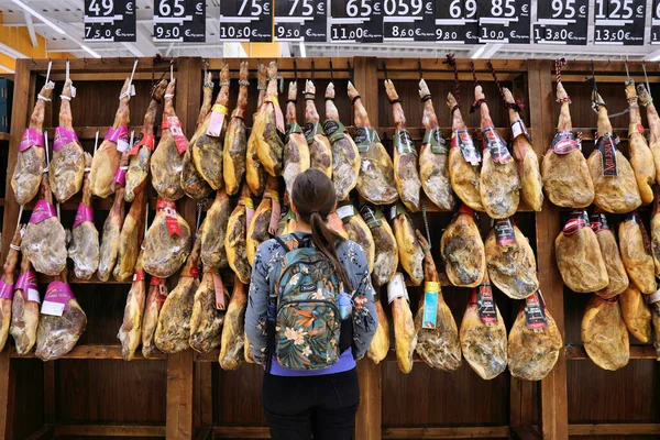 MADRID, SPAIN - 13 Nisan 2025: Müşteriler Madrid, İspanya 'da bir markette kurutulmuş domuz budu türündeki jambonlara bakıyorlar.
