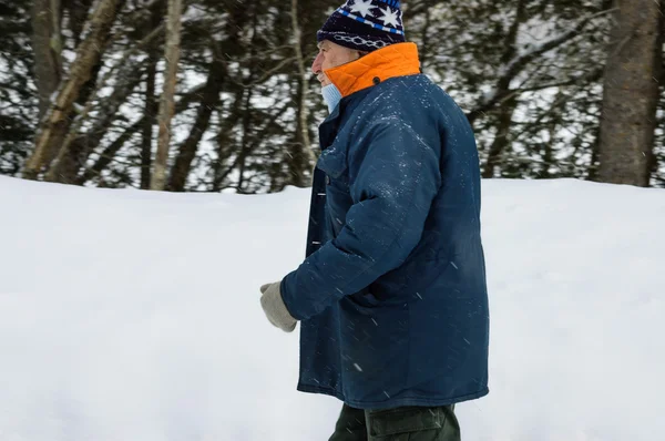 Senior caminando bajo la nieve — Foto de Stock