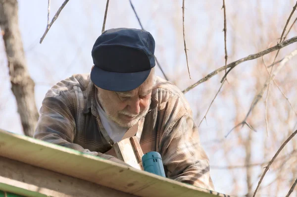Senior in een ladder het dak framing — Stockfoto