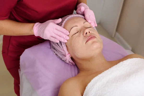 Face peeling mask, spa beauty treatment, skincare. Woman getting facial care by beautician at spa salon — Stock Photo, Image