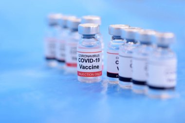 Aşı ve Sağlık Hizmetleri Tıbbi Konsepti. Korona virüsü enfeksiyonuna karşı önleme, aşılama ve tedavi için mavi zemin üzerinde aşılar