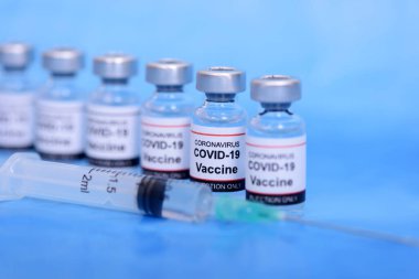 Aşı ve Sağlık Hizmetleri Tıbbi Konsepti. Korona virüsü enfeksiyonundan korunma, aşılama ve tedavi için mavi zemin üzerinde aşı ve şırınga