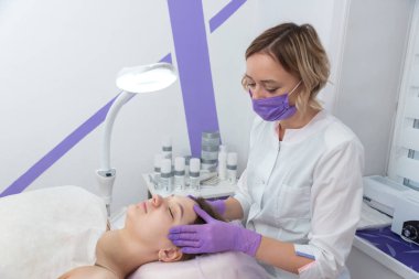 Kozmetik uzmanı genç kadın için kozmetik yüz tedavisine hazırlanıyor..