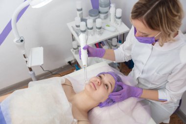 Güzellik salonu. Kozmetik uzmanı müşteri için su soyma prosedürü uyguluyor. Yan görüş. Profesyonel cilt bakımı kavramı.