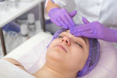 Kozmetik uzmanı genç kadın için kozmetik yüz tedavisine hazırlanıyor..