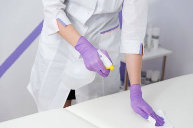 Bir kozmetolojistin ellerinde sıvı dezynfytsyrovaly yüzeyi.