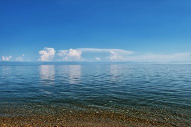 Baykal Gölü 'nde şeffaf su, bulutlar ve taşlar var.