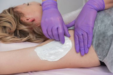 Balmumu tüyü temizleme konsepti. Beyaz balmumu ile kaplıca salonu, beyaz arka plan, koltuk altı kız tüy işleme.