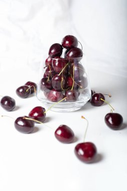 Beyaz arka planda cam kasede olgun kirazlar