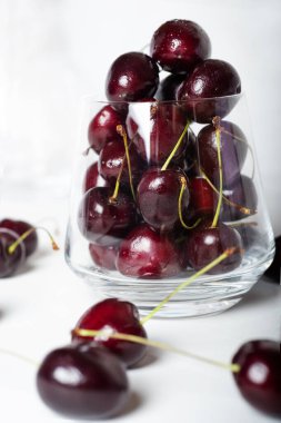 Beyaz arka planda cam kasede olgun kirazlar