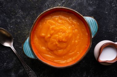 Ahşap siyah masada sunulan hindistan cevizi sütlü fırında balkabağı kreması. Düz yat. yemek ve sağlıklı yaşam konsepti