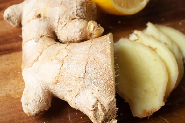 Ahşap masada taze zencefil baharatı kesiyor. Sağlıklı bir kavram. Düz yat. Kapat.