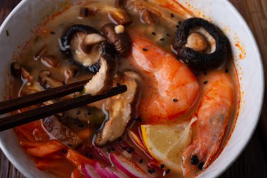 Midye, karides, şitake mantarı ve sebzeli miso çorbası. Koyu kahverengi ahşap masada servis ediliyor. düz yat