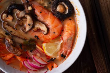 Midye, karides, şitake mantarı ve sebzeli miso çorbası. Koyu kahverengi ahşap masada servis ediliyor. düz yat