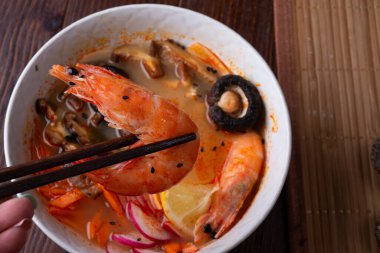 Midye, karides, şitake mantarı ve sebzeli miso çorbası. Koyu kahverengi ahşap masada servis ediliyor. düz yat