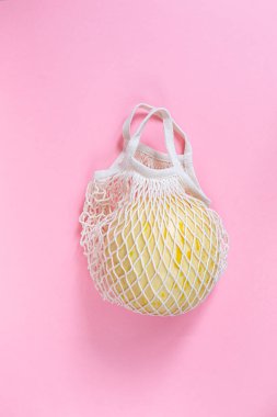 Pembe arka planda, çevre dostu pamuk örgüsü içinde olgun kavun. Boşluğu kopyala. Üst yaşam