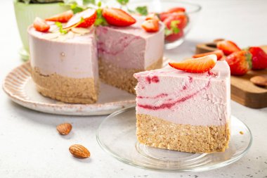 Badem, yulaf unu, kuru üzüm ve hindistancevizi ezmesi, kaju ve çilekli mus, glüten, yumurta ve şekersiz nefis bir dilim vejetaryen pastası. Sağlıklı yiyecekler.